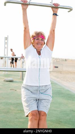Old woman hanging from pull-up bar Stock Photo