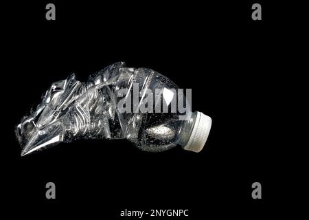 Crushed plastic mineral water bottle isolated against a black background Stock Photo