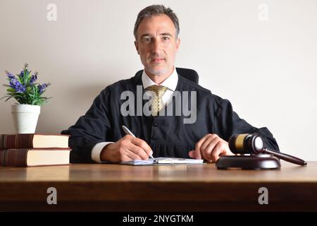 Judge working in his office looking straight ahead reviewing documents on a wooden table. Front view Stock Photo