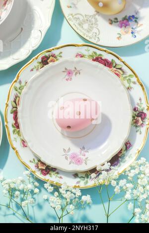 Aesthetic Easter composition made of colorful plates, cups and golden eggs; Easter concept, vintage style, pastel colors Stock Photo