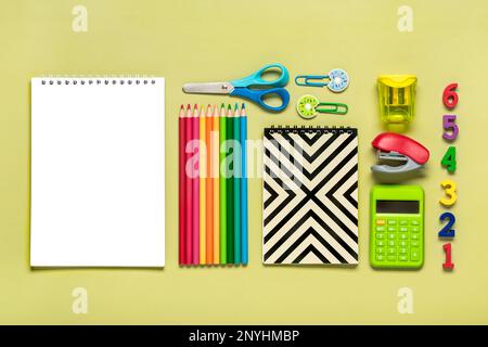 Frame from school and office supplies Paper clips, pens, calculator, sharpener, notepad, stapler isolated on green background Flat lay Top view Back t Stock Photo
