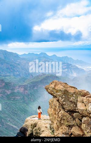 Aerial perspective shot of female hiker in standing posture on top of mountain at gran Canaria, popular touristic attraction of spain Stock Photo