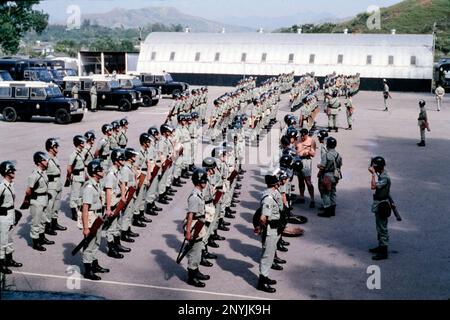 Training Company Inspection, Parade square at volunteer slopes, Police Tactical Unit, (Royal Hong Kong Police) Fanling, New Territories, Hong Kong 1979. British-made Land Rover 4WDs and a Nissan Hut in the background. Stock Photo
