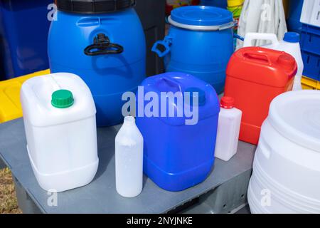 A lot of plastic packaging lies on a wooden floor. Plastic bottles of different sizes, plastic containers, canisters boxes for anything Environmental Stock Photo