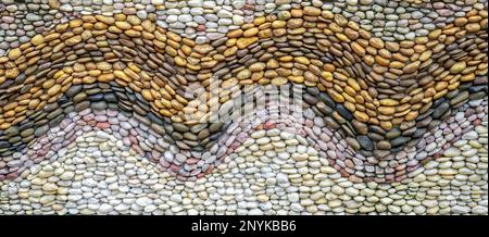Pebbles stone wall texture background. Pebbles mosaic. Wave pattern design beach pebbles on concrete wall abstract background. Embedding individual Stock Photo