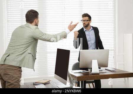 Emotional colleagues arguing in office. Toxic work environment Stock Photo