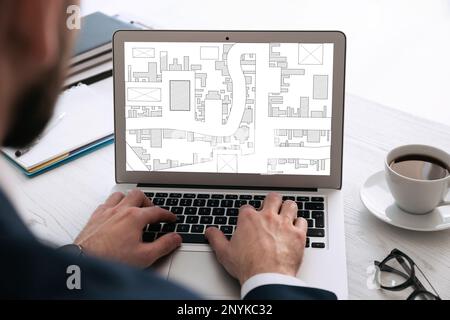 Man analyzing cadastral map on laptop at table, closeup Stock Photo