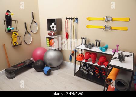 Many different sports equipment in room with beige walls Stock Photo