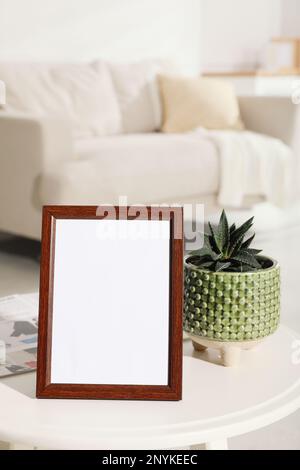 Empty photo frame, magazine and succulent on white table in living room Stock Photo