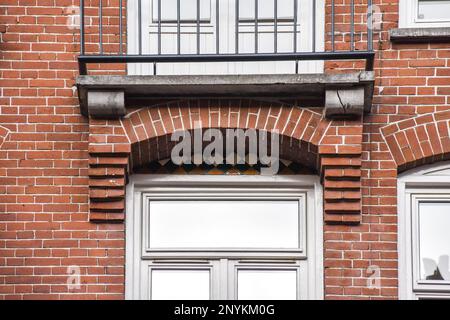 a brick building with a clock on it's side and the window frame is open to reveal an outside view Stock Photo