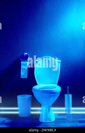 Toilet bowl in public restroom lit with UV blue light Stock Photo