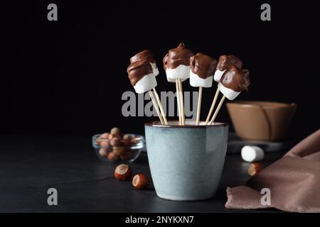 Delicious marshmallows covered with chocolate on black table Stock Photo