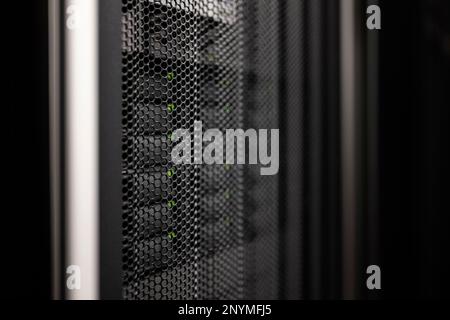 gray black server cabinet door made of perforated metal with network storage hard drives with green leds behind Stock Photo