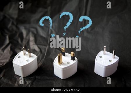 Choosing from various electric plug adapters. Difficulties and problems of traveling around the world. Black and white Stock Photo