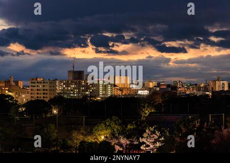 Dramatic clouds after sunset over low rise buildings by park Stock Photo