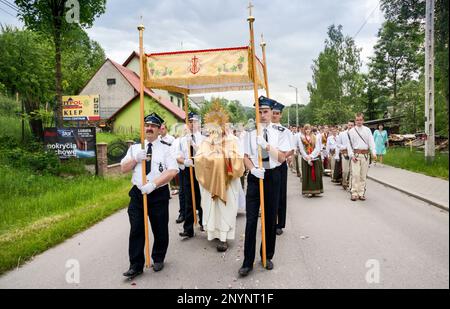 Village priest holding a monstrance, firefighters carrying a baldachin,  Corpus Christi procession in Skomielna Czarna, Gorals (Polish highlander people) village, Beskids mountain range, Western Carpathians, Malopolska region, Poland Stock Photo