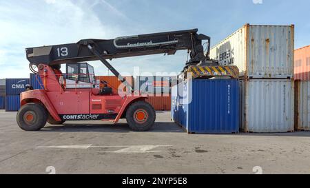 Dobanovci, Serbia - March 3, 2017: Reach Stacker Lifting Shipping Container at Cargo Terminal Yard. Stock Photo