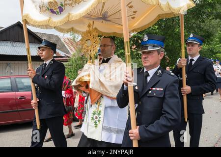 Village priest holding a monstrance, firefighters carrying a baldachin, Corpus Christi procession in Tokarnia, Gorals (Polish highlander people) village, Beskids mountain range, Western Carpathians, Malopolska region, Poland Stock Photo