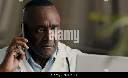 African american mature doctor medical specialist consulting remote calling mobile phone male therapist general practitioner discuss healthcare Stock Photo