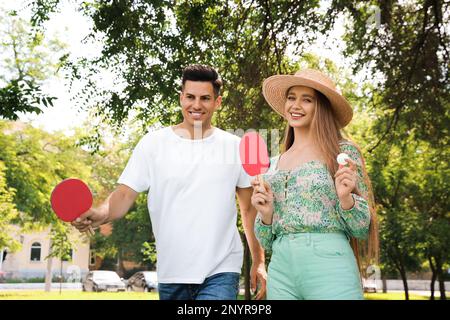 Happy couple with ping pong rackets and ball in park Stock Photo