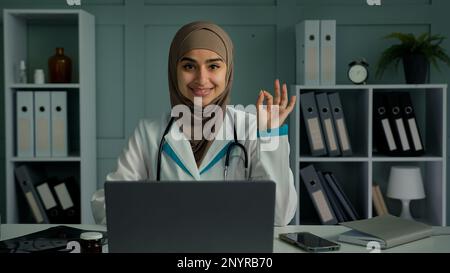 Glad happy arabian middle-eastern doctor young islamic religion woman practitioner therapist cardiologist dentist medical worker in white coat Stock Photo