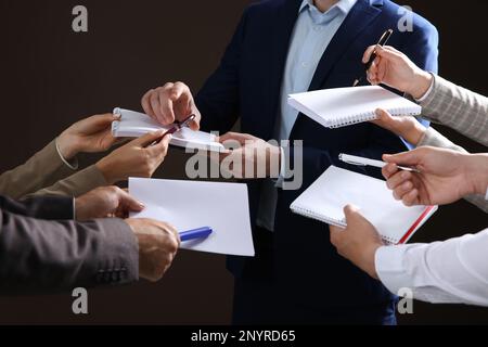 Man signing autograph in notebooks on dark background, closeup Stock Photo