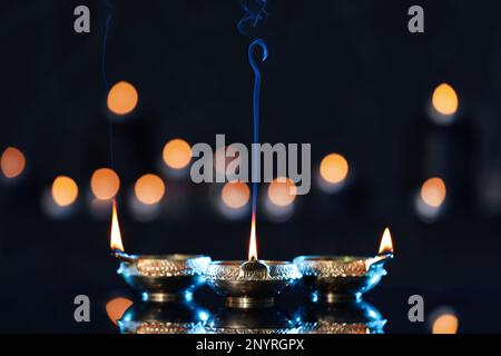 Lit diyas on table against blurred lights. Diwali lamps Stock Photo