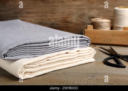 Folded hemp cloths and scissors on wooden table, closeup Stock Photo