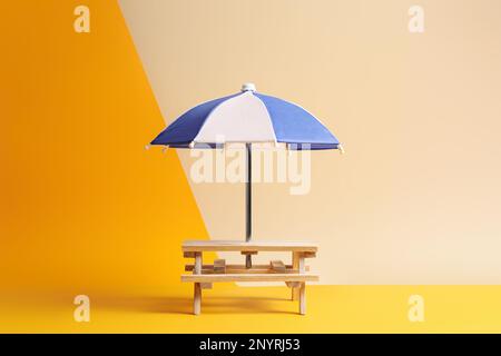 Small wooden holder with toy umbrella on color background Stock Photo