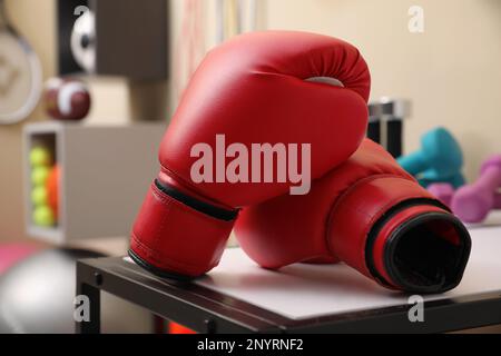 Red boxing gloves on white table in room with other sports equipment Stock Photo