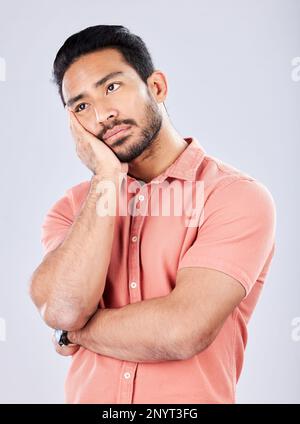 Sad, depression and bored with a man in studio on a gray background feeling lonely or unhappy. Thinking, boredom and alone with a handsome young male Stock Photo