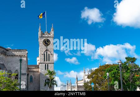 View of an historic building with a tower in Bridgetown, Barbados, West Indies with clock and flag and tree lined street. Stock Photo