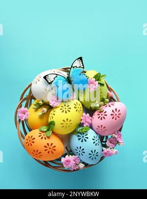 Multi colors Easter eggs in the basket and flowers on blue background. Pastel color Easter eggs Stock Photo