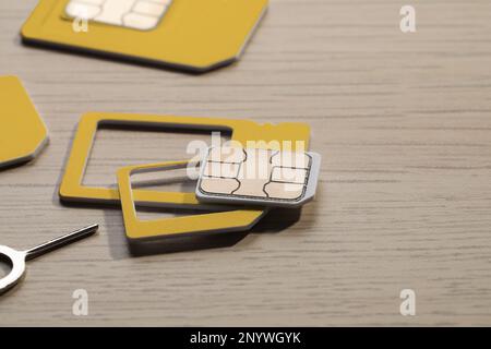 Different SIM cards and ejector on wooden background, closeup Stock Photo