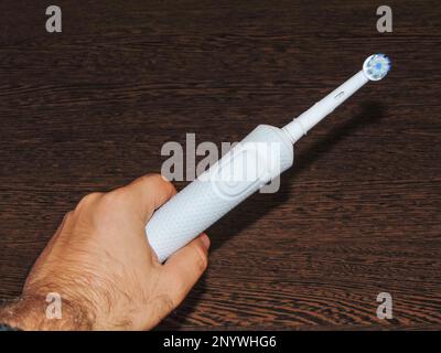 white electric toothbrush in one hand Stock Photo