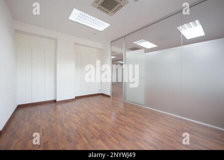 Empty office with technical ceilings, white walls with friezes and tempered glass separating wall with transparent door Stock Photo