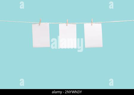 Clothespin hanging with blank photo papers on color background Stock Photo