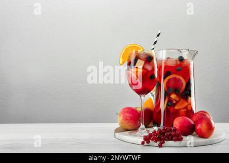 Glass and jug of Red Sangria on white wooden table against light grey background. Space for text Stock Photo
