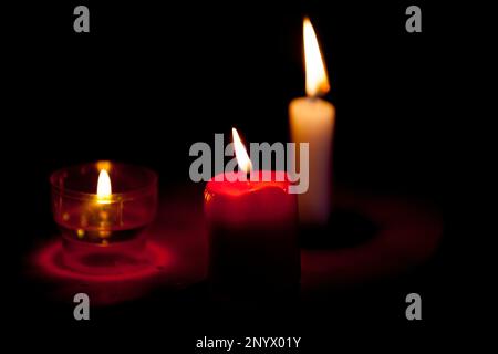 Close-up on a three candles lit in the dark Stock Photo