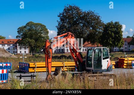 Excavator at the construction site. Orange plastic pipes in the background. Stock Photo