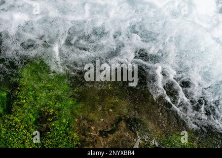 Foaming clear water and green algae at the bottom. View from above. Stock Photo