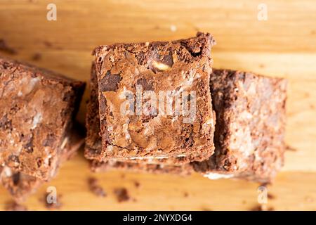 A overhead view of home baked chocolate pecan Brownies arranged on a wooden platter. The blondies are still warm and gooey. an indulgent treat Stock Photo