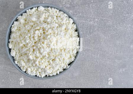 Cottage cheese in plate gray concrete background, top view Stock Photo