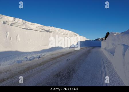 Snowbanks tower over a road in Mammoth Lakes, CA after storms dumped over 10 feet of snow on the Sierra Nevada town. Stock Photo