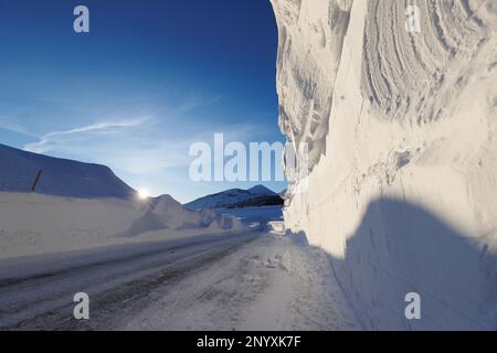 Snowbanks tower over a road in Mammoth Lakes, CA after storms dumped over 10 feet of snow on the Sierra Nevada town. Stock Photo