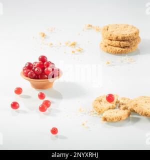 Saucer with bright cranberries and oatmeal cookies laid out for breakfast on a glass table. Stock Photo