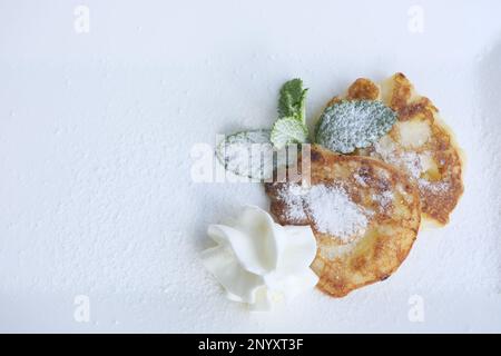 pancakes on white rectangular plate with mint leaves and powdered sugar sprinkled serving dessert Healthy food pancakes with apples berries lunch Grandma's kitchen for children Stock Photo
