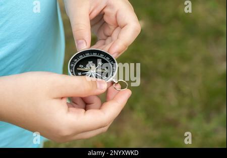 Anonymous elementary school age child holding a compass in hands, closeup, world directions, travel, journey, exploration symbol abstract concept, obj Stock Photo