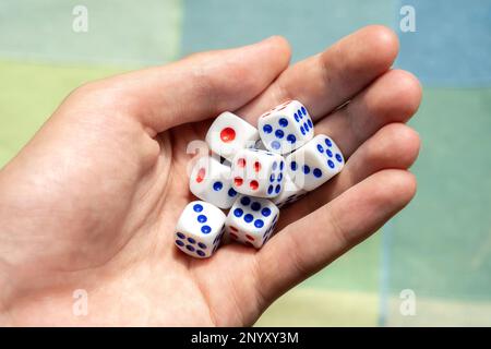 Man holding a few small game dice showing different numbers in hand, group of objects closeup. Math randomness, entropy, probability and statistics, e Stock Photo