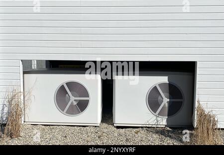 Newly installed heat pumps providing clean energy in front of a house. The topic of energy transition and rising electricity prices. Stock Photo